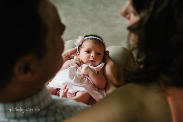 top down photo of newborn baby girl looking up at parents while they look at her