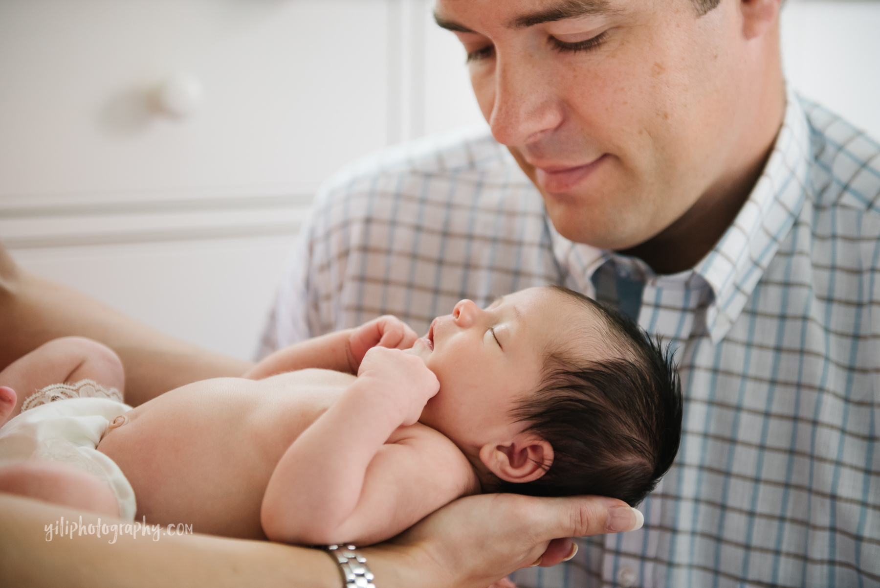 father looking adoringly at his newborn baby held by mother