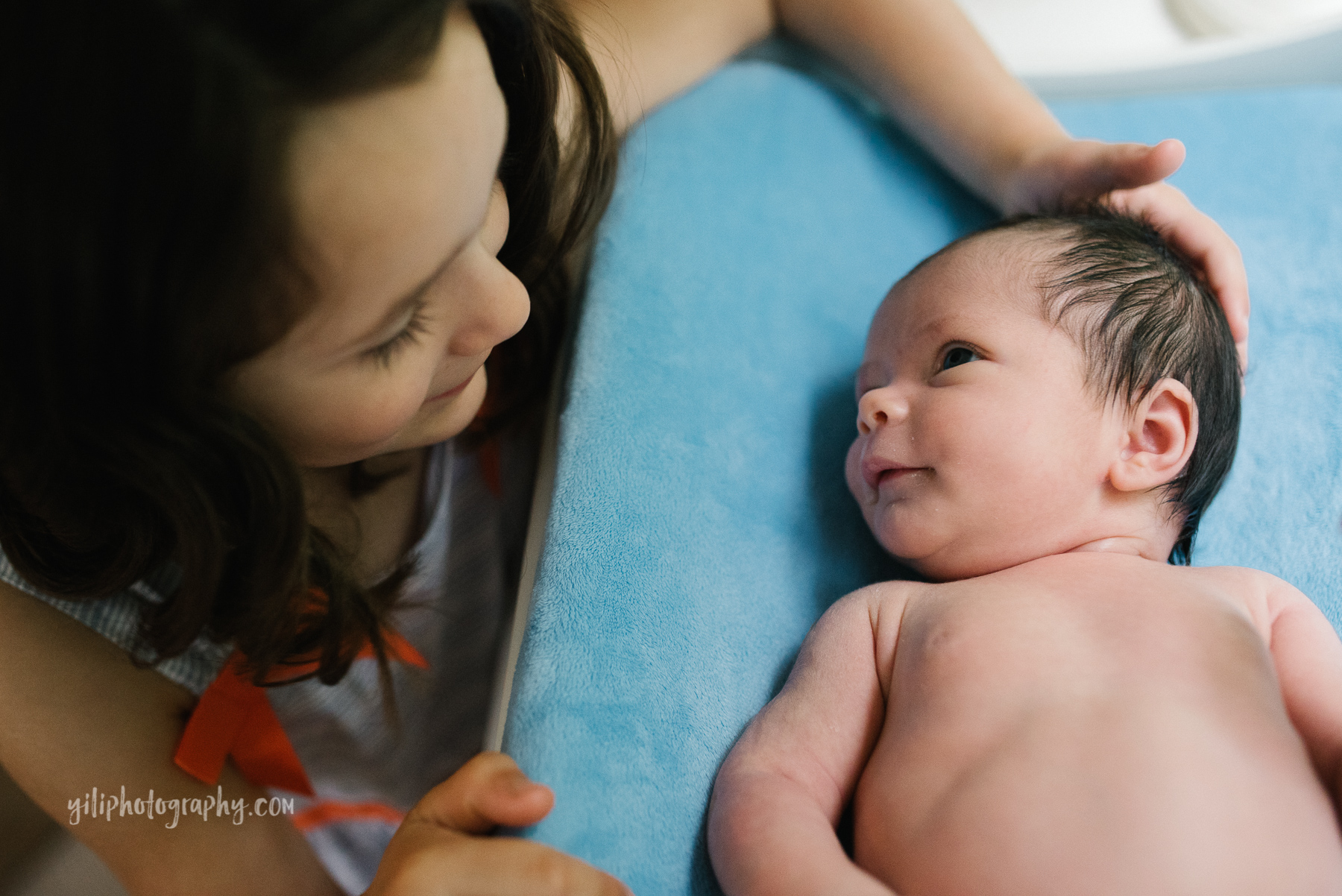 big sister patting her baby sister laying on changing table