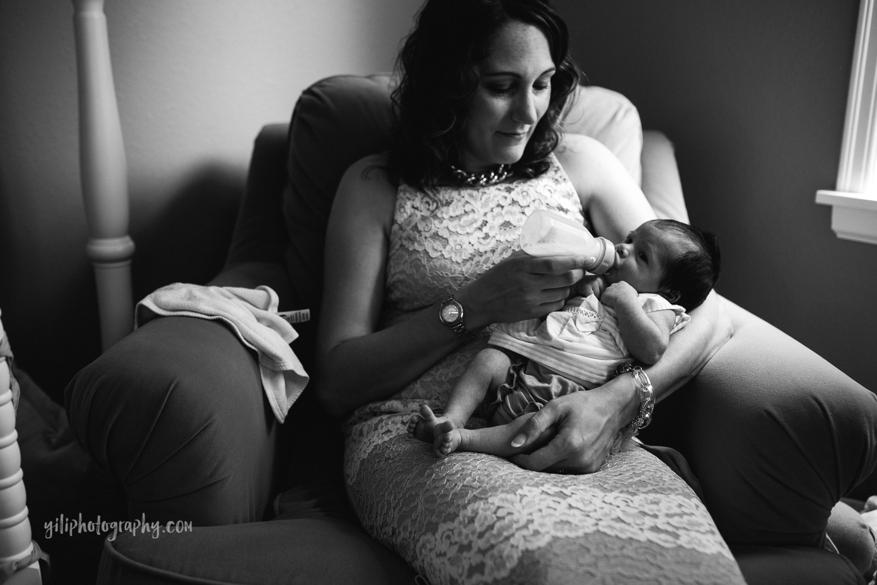 mom sitting in rocker feeding newborn baby a bottle