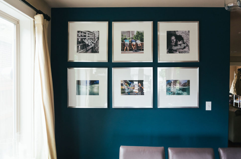 large square framed photographs in wall gallery on blue dining room wall