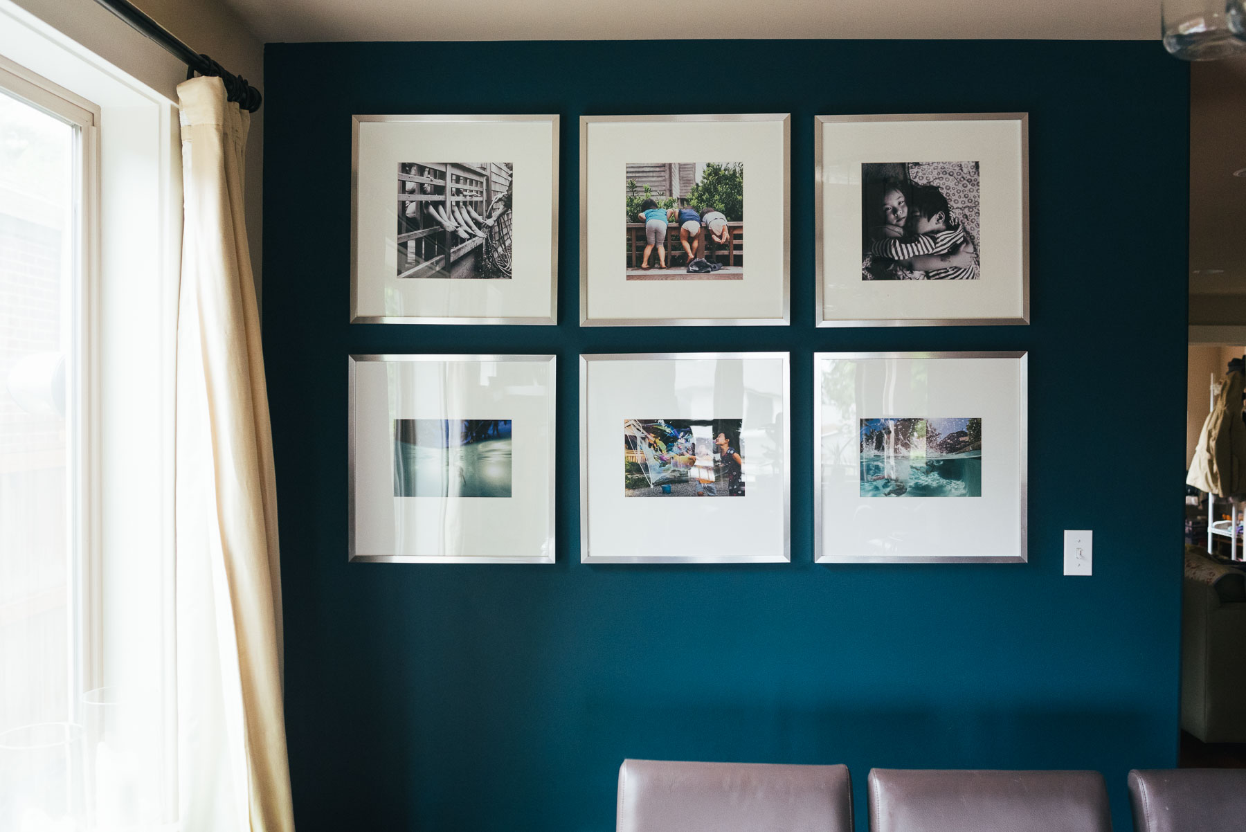 large square framed photographs in wall gallery on blue dining room wall