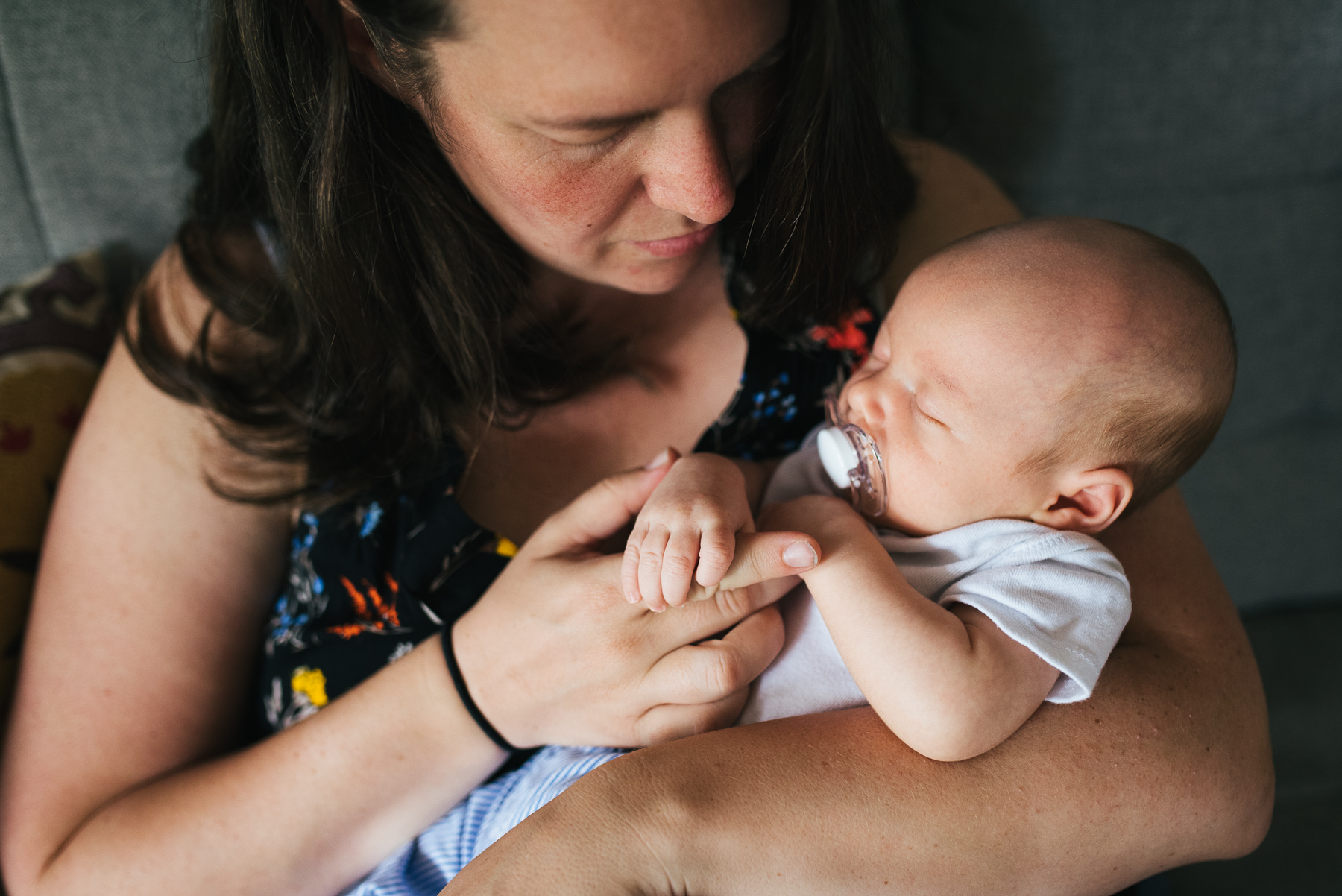 close-up of mom holding hands with sleeping newborn with pacifier