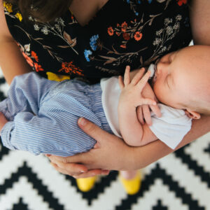 Top-down photo of mom holding sleeping newborn baby in her arms