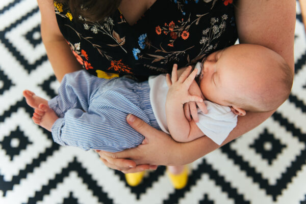 Top-down photo of mom holding sleeping newborn baby in her arms