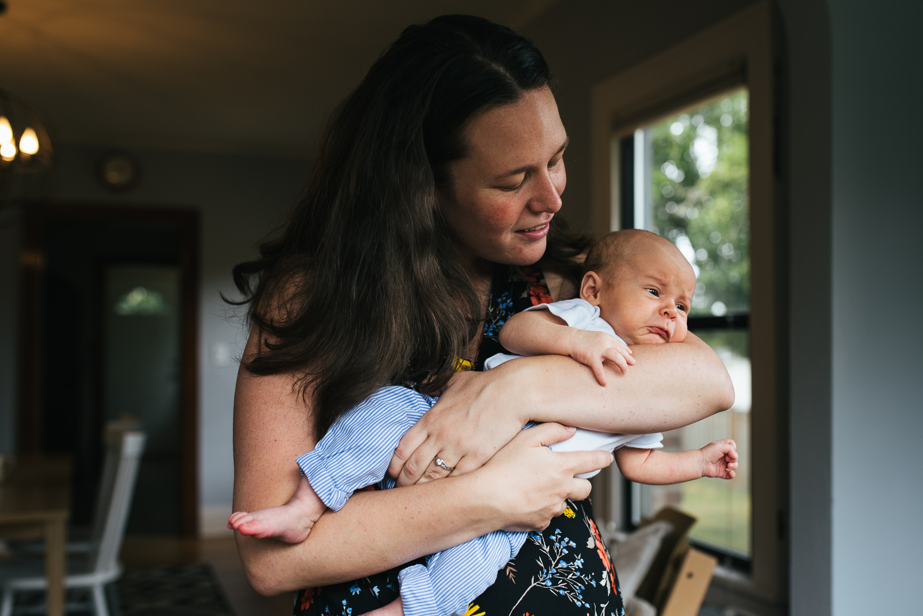 mom holding newborn son in dining room while he is upset