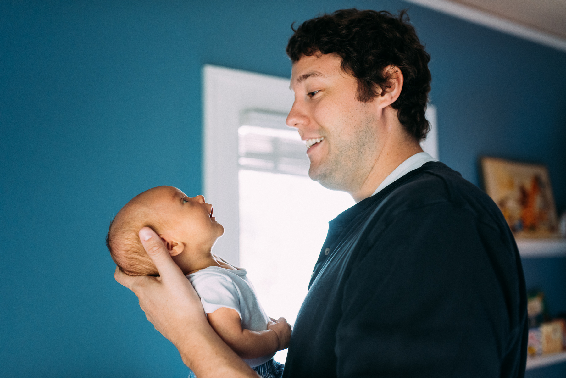 new father talking to newborn baby in nursery