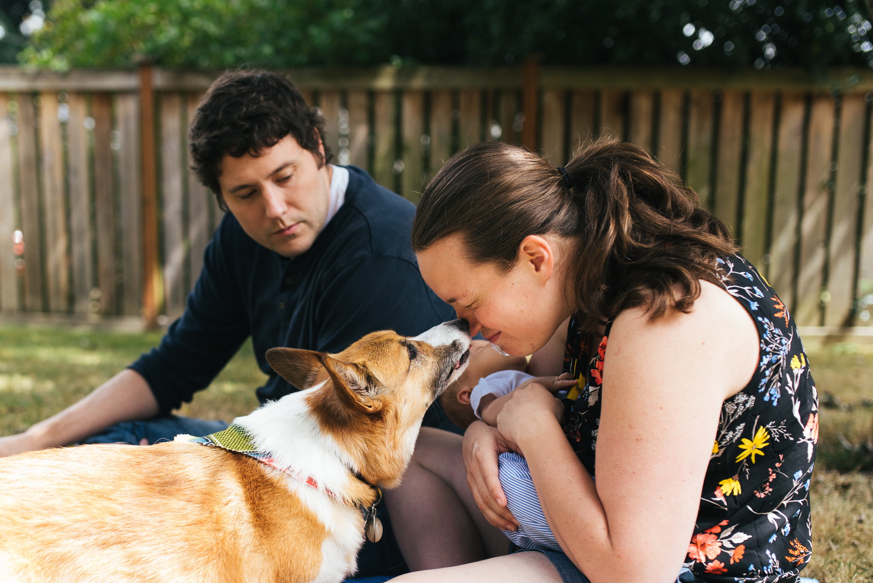 woman giving dog a kiss while sitting in yard with husband