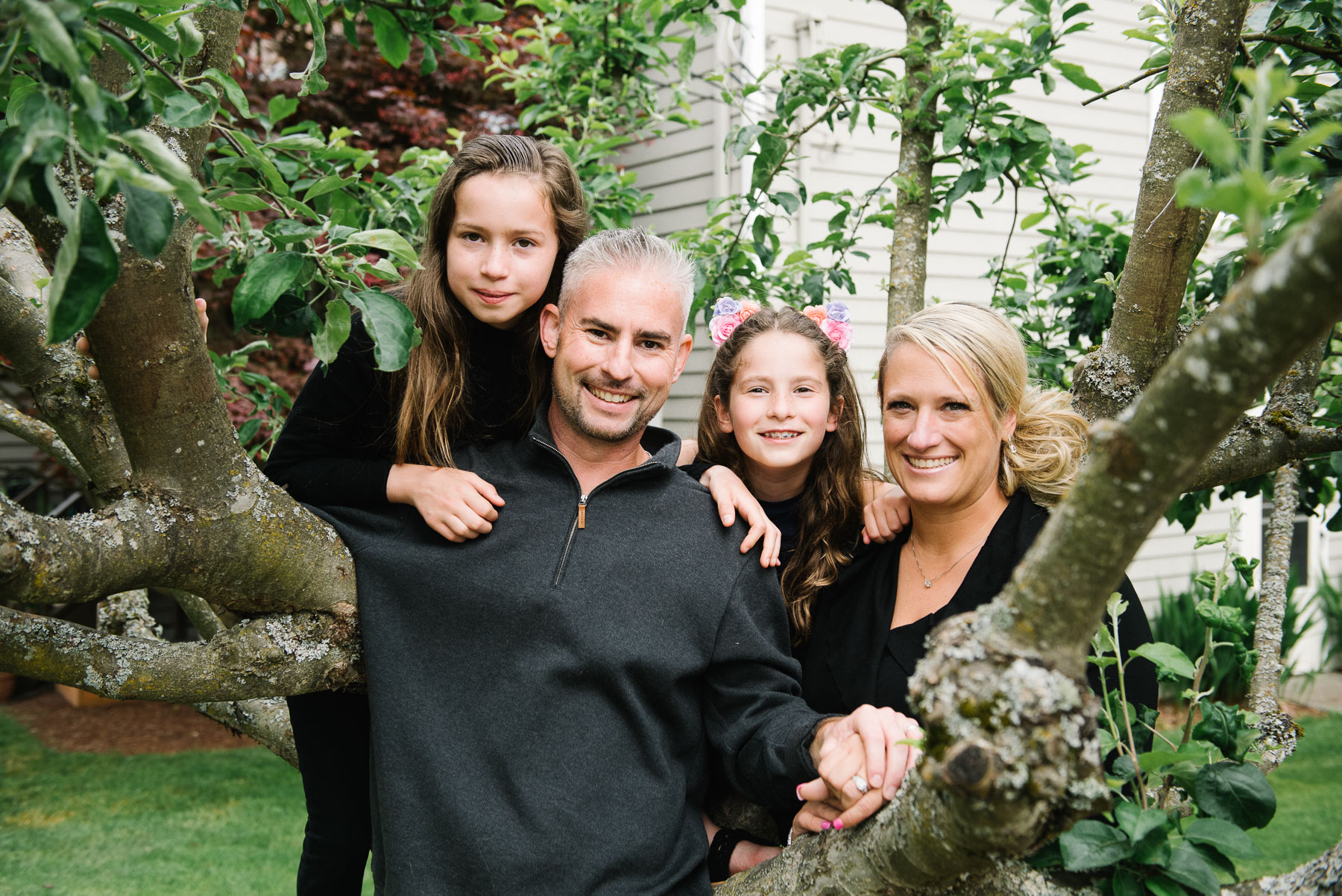 mother and father with two daughters posing in their apple tree