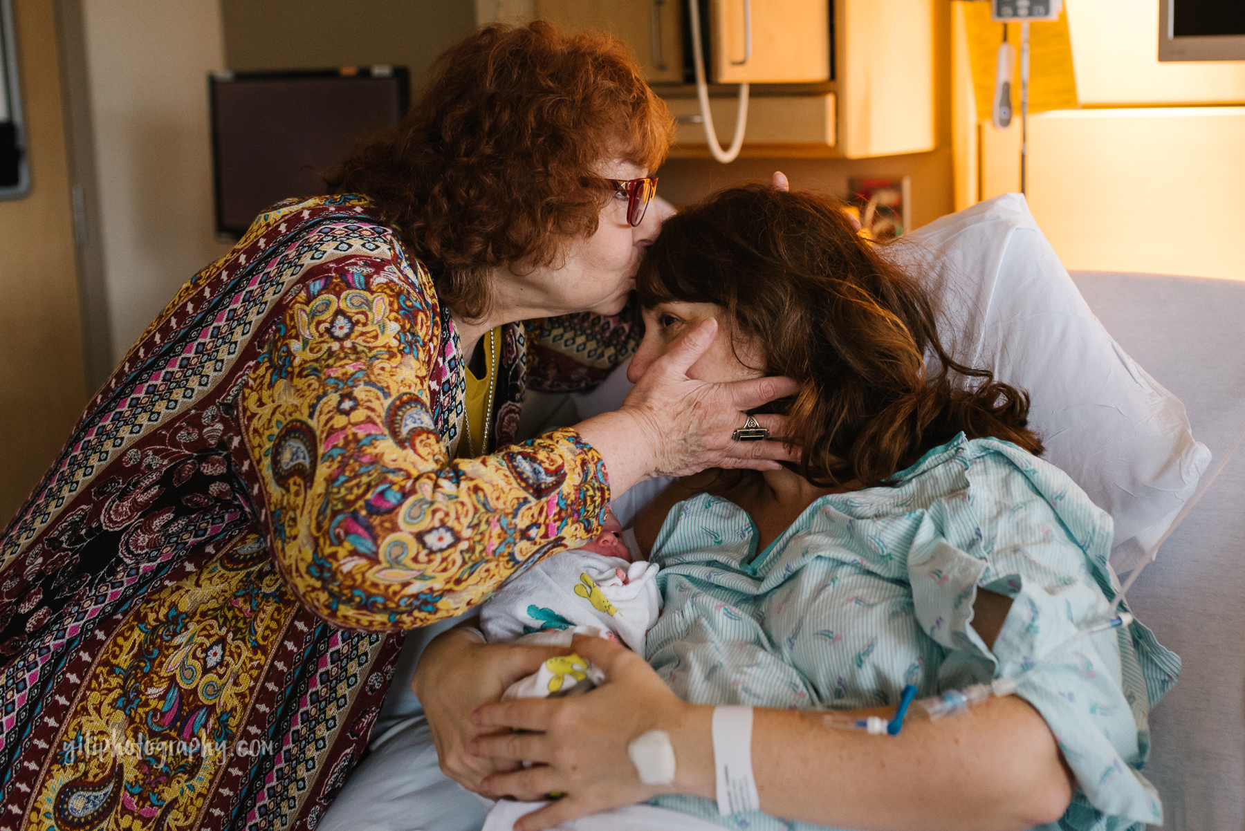 grandmother kisses her daughter who just gave birth