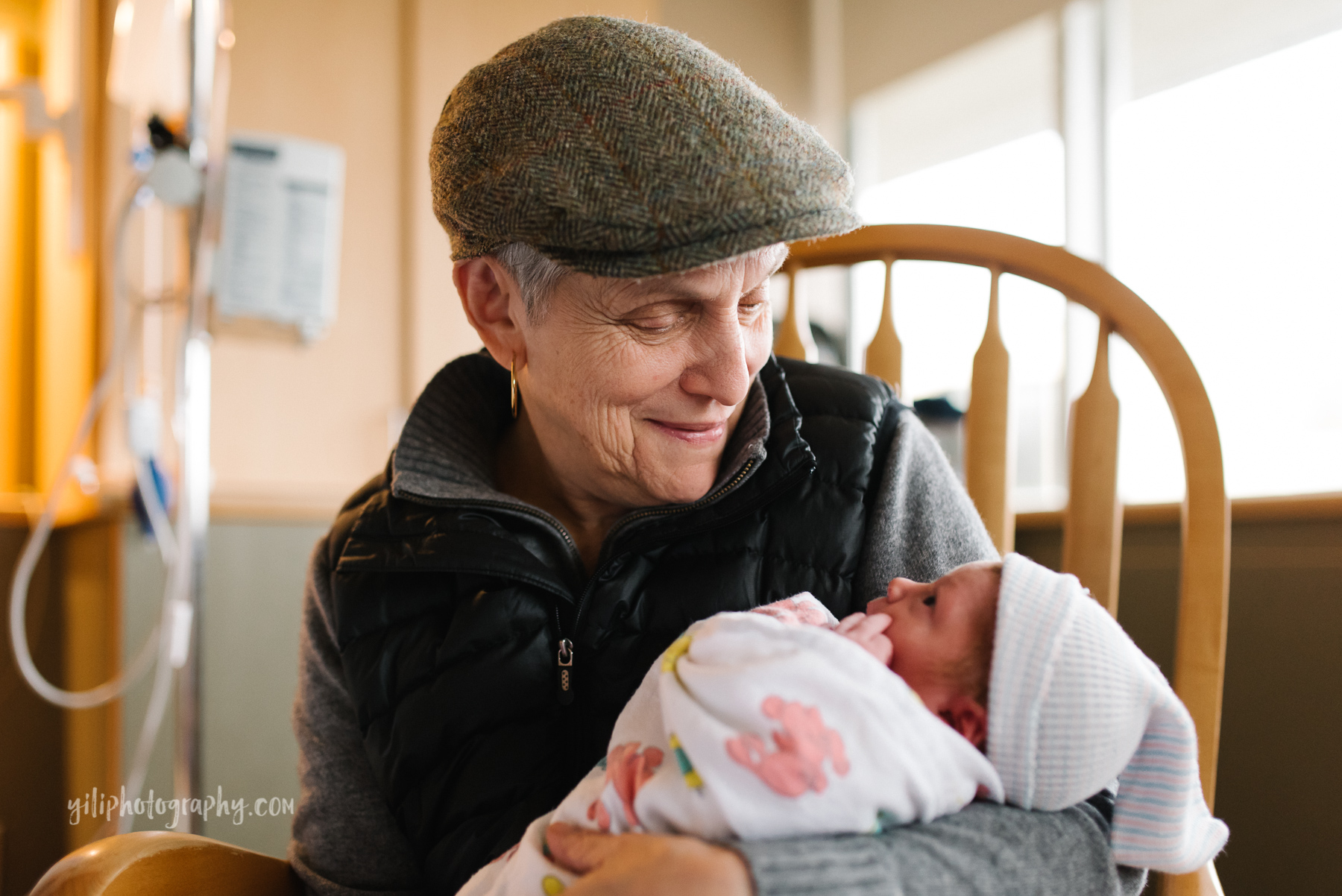paternal grandmother holds newborn baby while looking lovingly at her