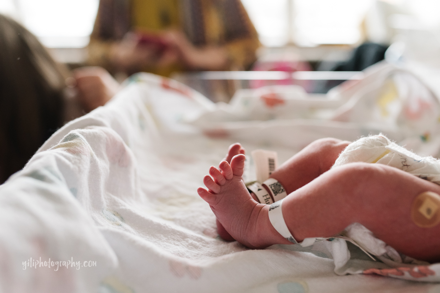 close up of baby's feet and toes with ID bracelets in bassinet 