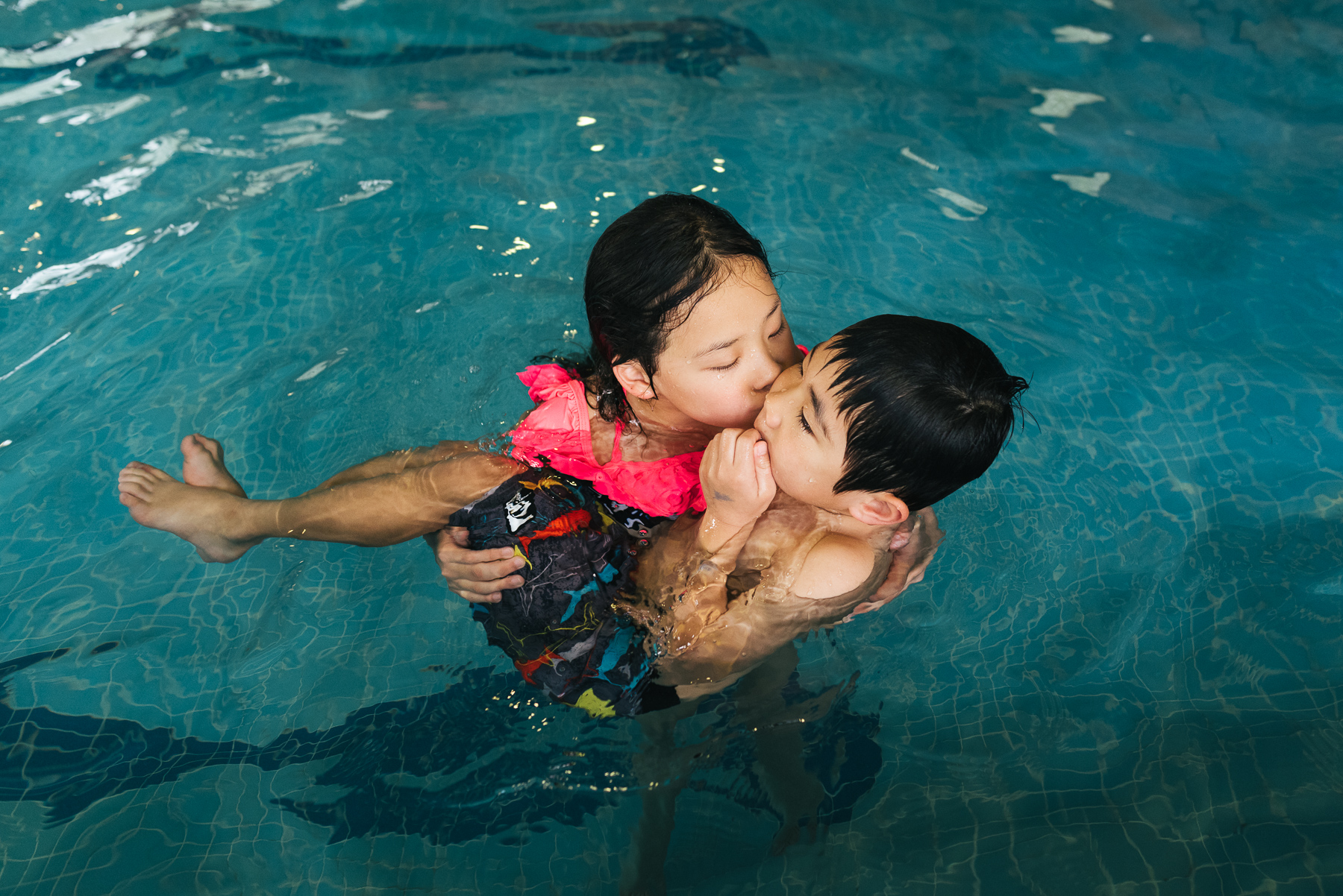 big sister cuddling with little brother in pool