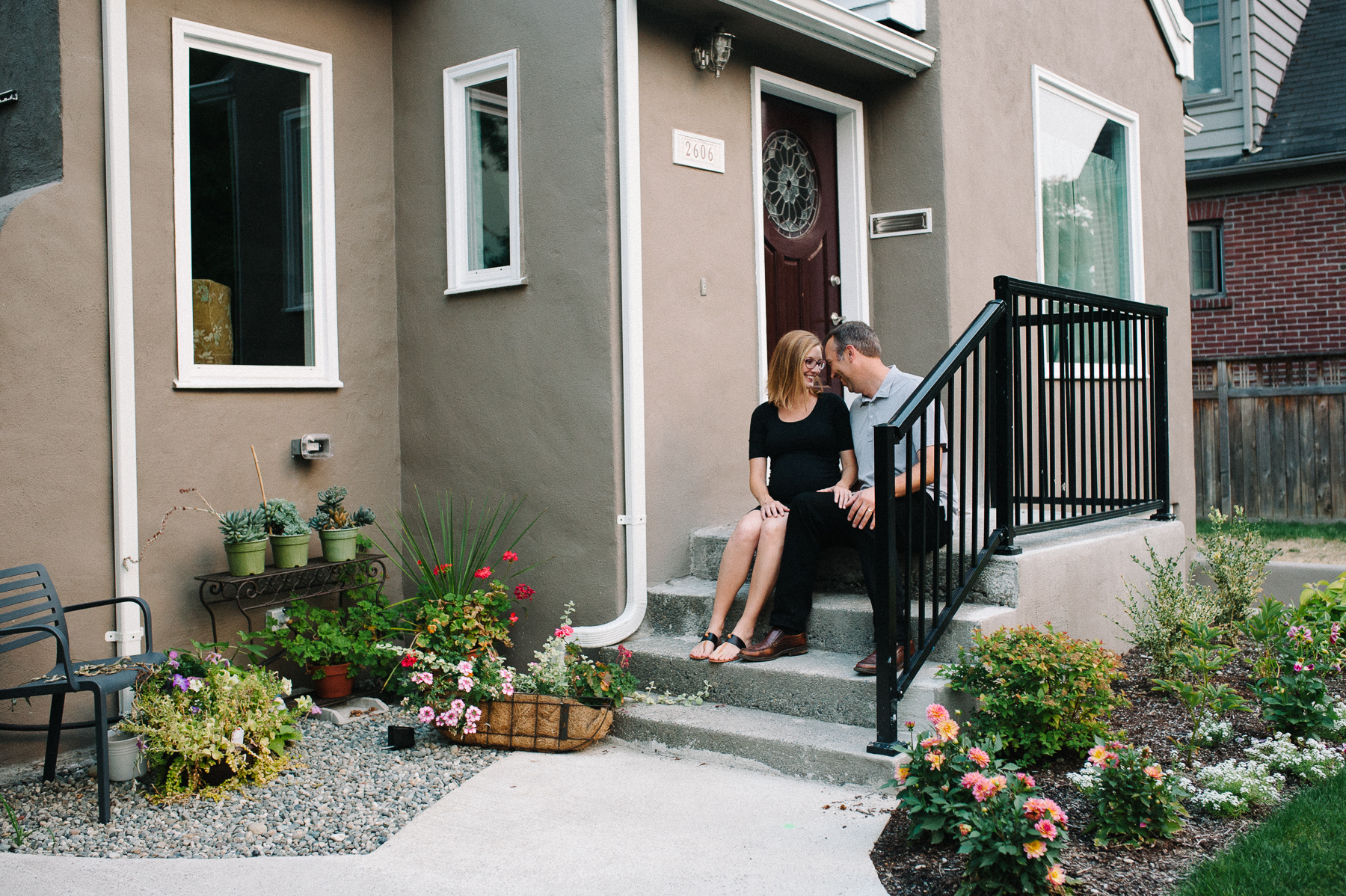 maternity photo of couple sitting on front porch steps of home