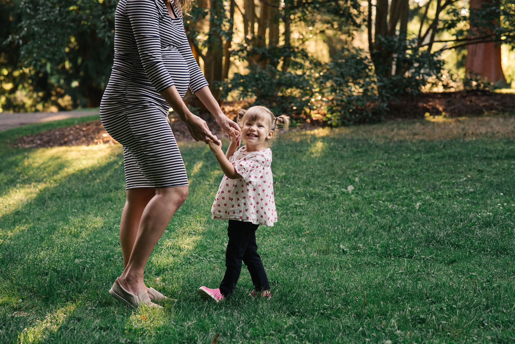 pregnant mother holding hands with two year old daughter