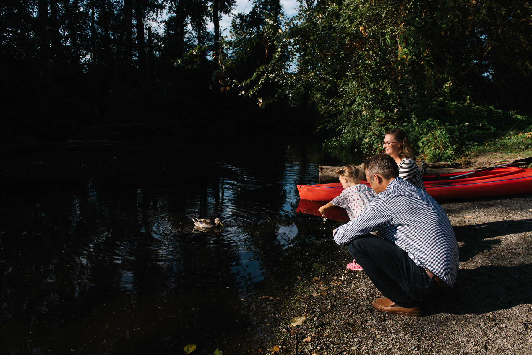 family at edge of pond feeding ducks