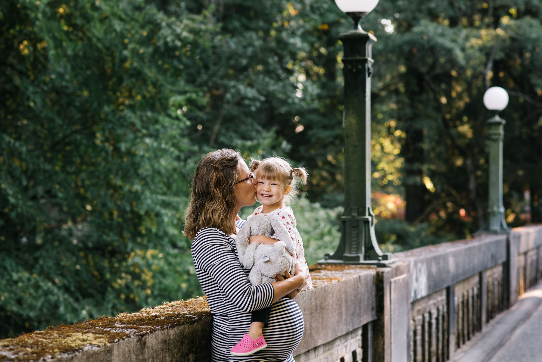 pregnant mother kissing two year old on cheek on footbridge in washington park arboretum