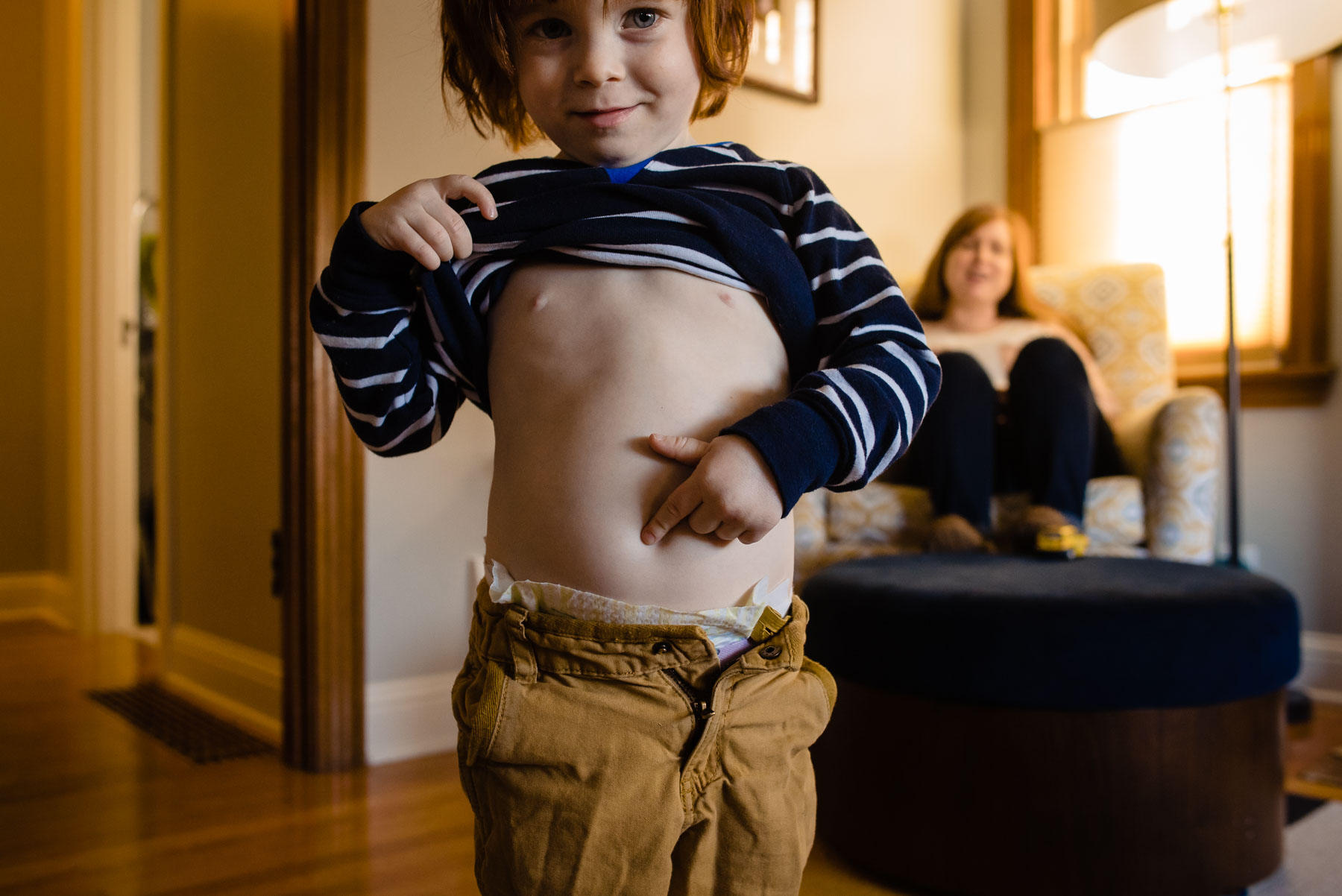 toddler boy lifting shirt pointing to belly button