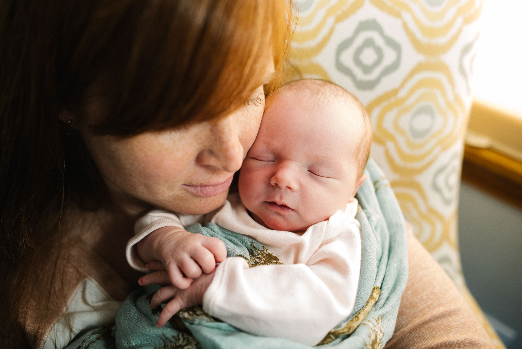 red head mom snuggling newborn baby girl