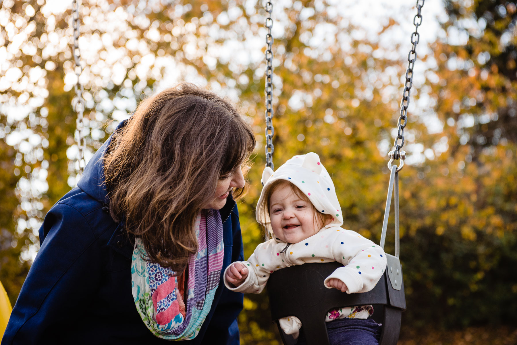 mom talking to baby on swing at playground