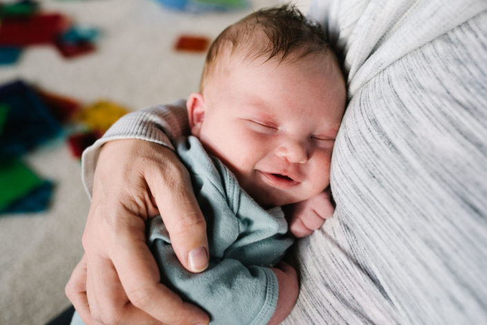 newborn baby smiling in mom's arms