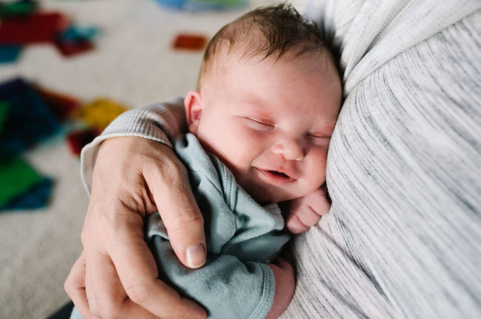 newborn baby smiling in mom's arms