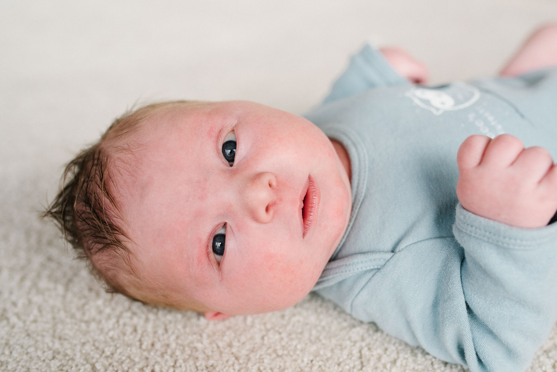 newborn baby boy laying on carpet at home