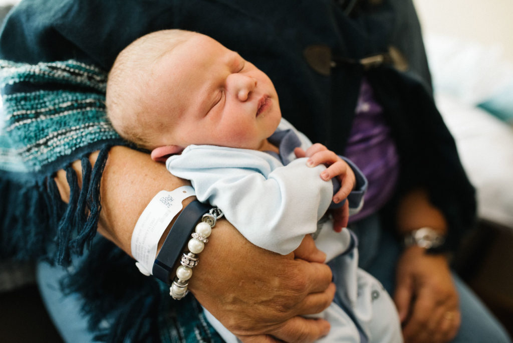 newborn baby in hospital being held by grandmother