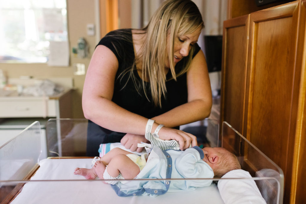 mother interacting with newborn baby in hospital bassinet