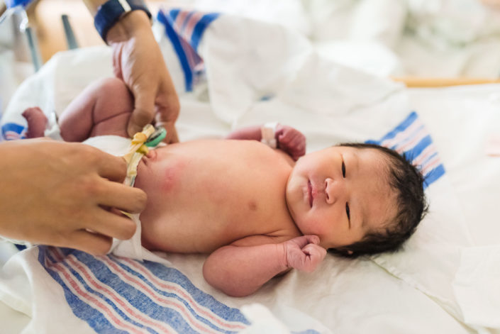 dad changing newborn baby diaper in hospital