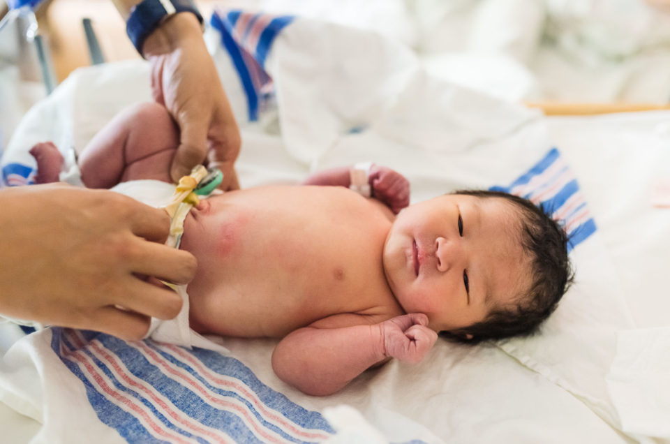 dad changing newborn baby diaper in hospital