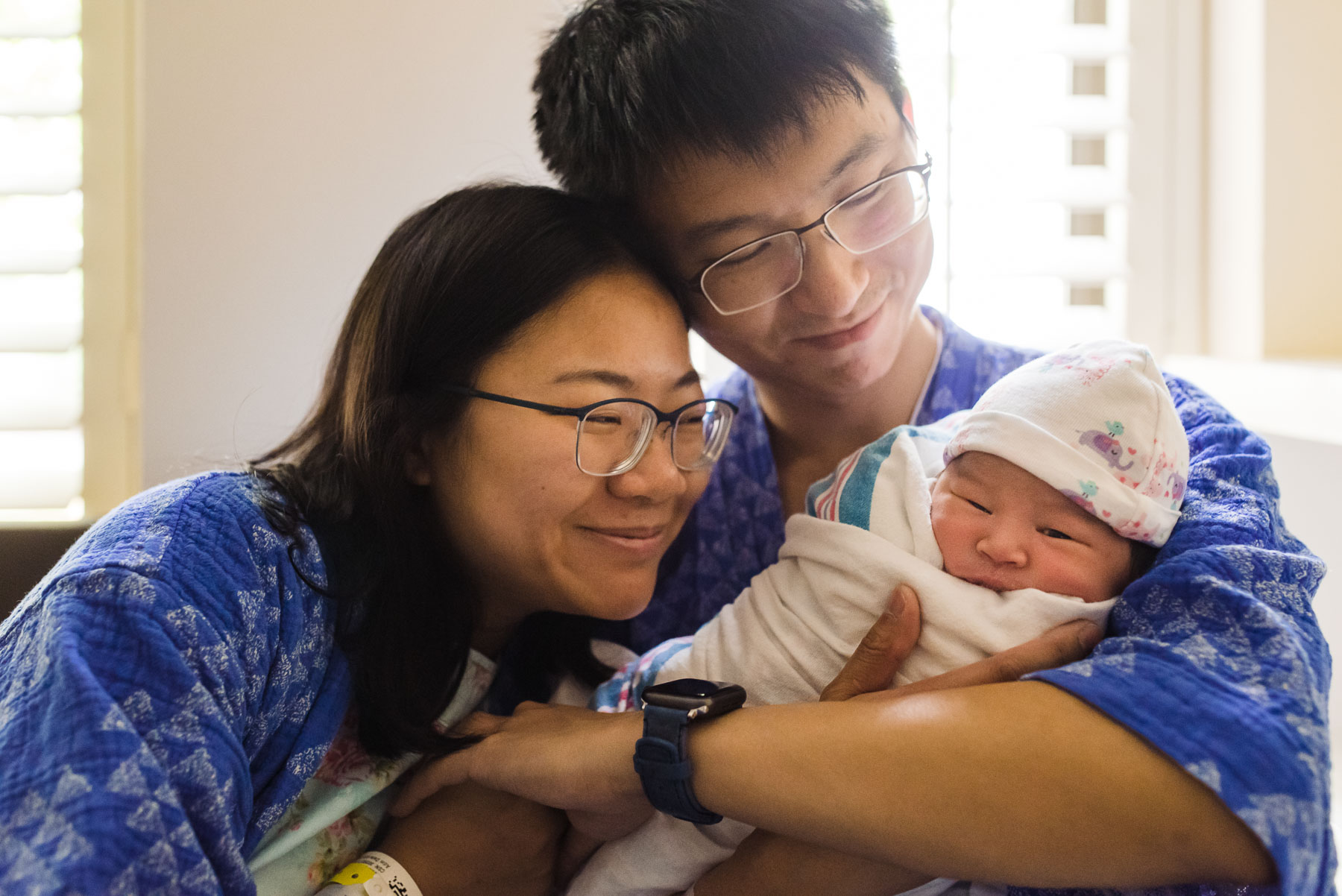 mom and dad looking lovingly at newborn baby