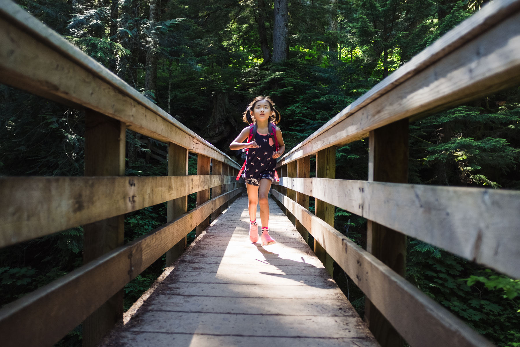 Little Asian girl crossing bridge on Denny Creek trail hike