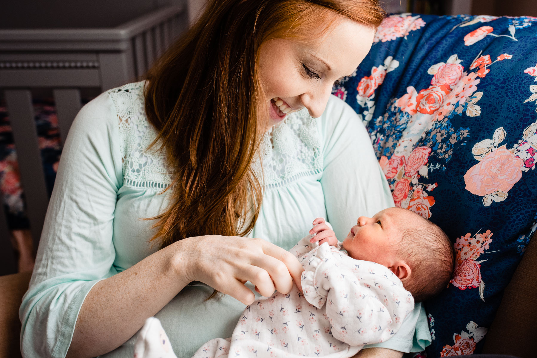 mother looking lovingly at newborn baby girl in home nursery