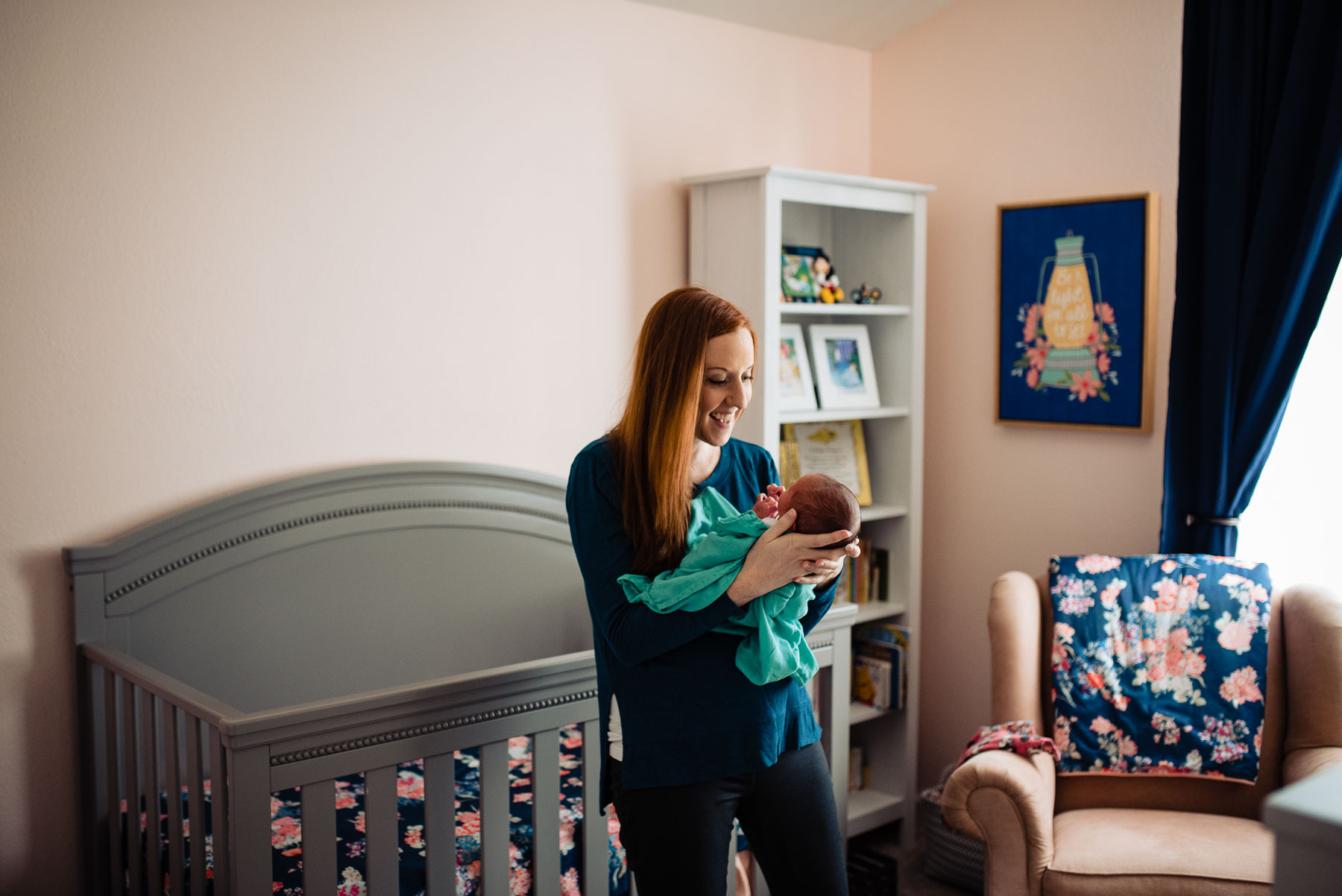 mother swaying and talking to newborn baby in nursery