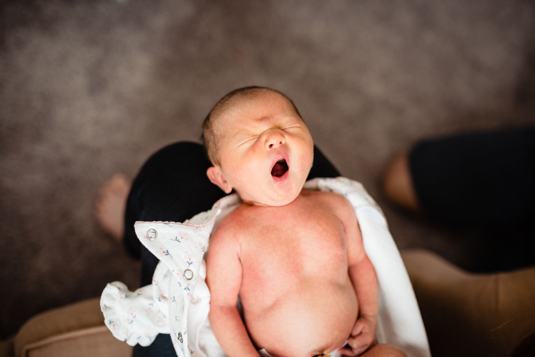 newborn baby yawning in mother's lap