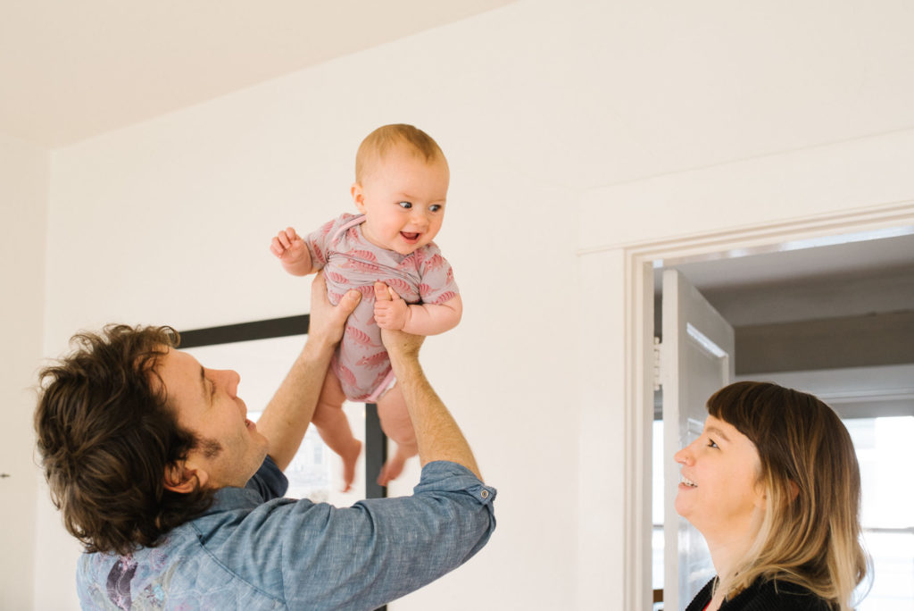 dad lifting baby above his head at home