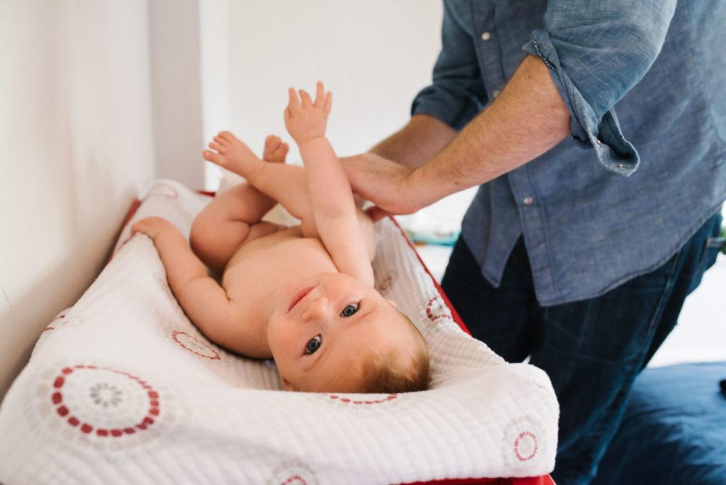 dad changing baby's diaper on changing table