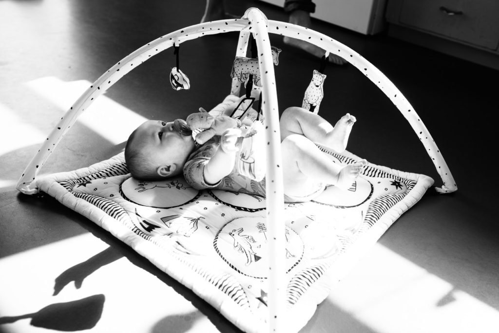 baby playing on baby gym with bright sun