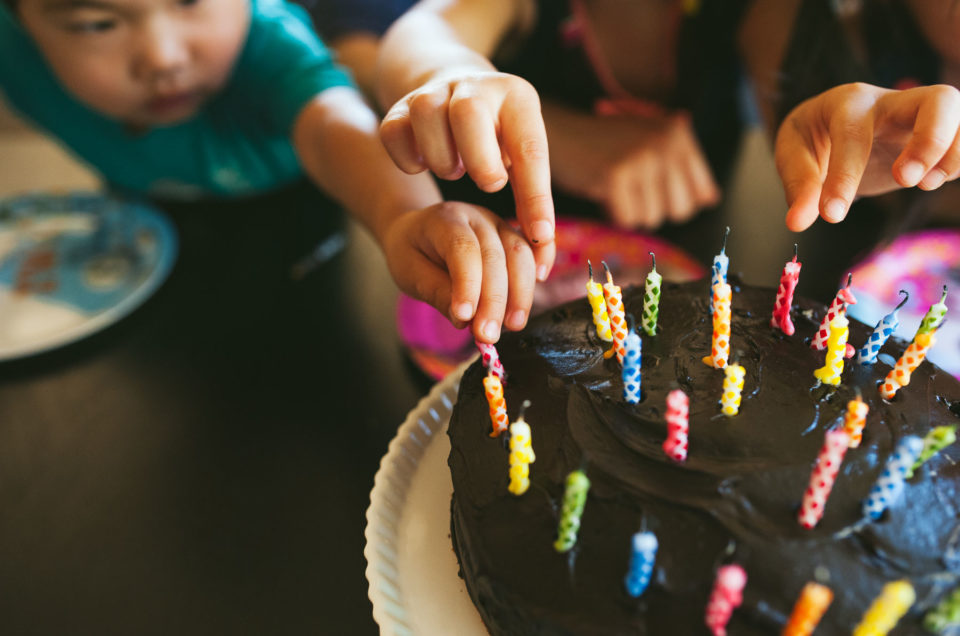 kids picking candles out of birthday cake