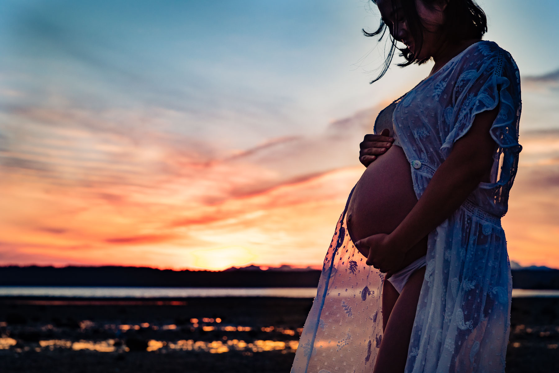 pregnant woman at beach at sunset in flowy sheer dress