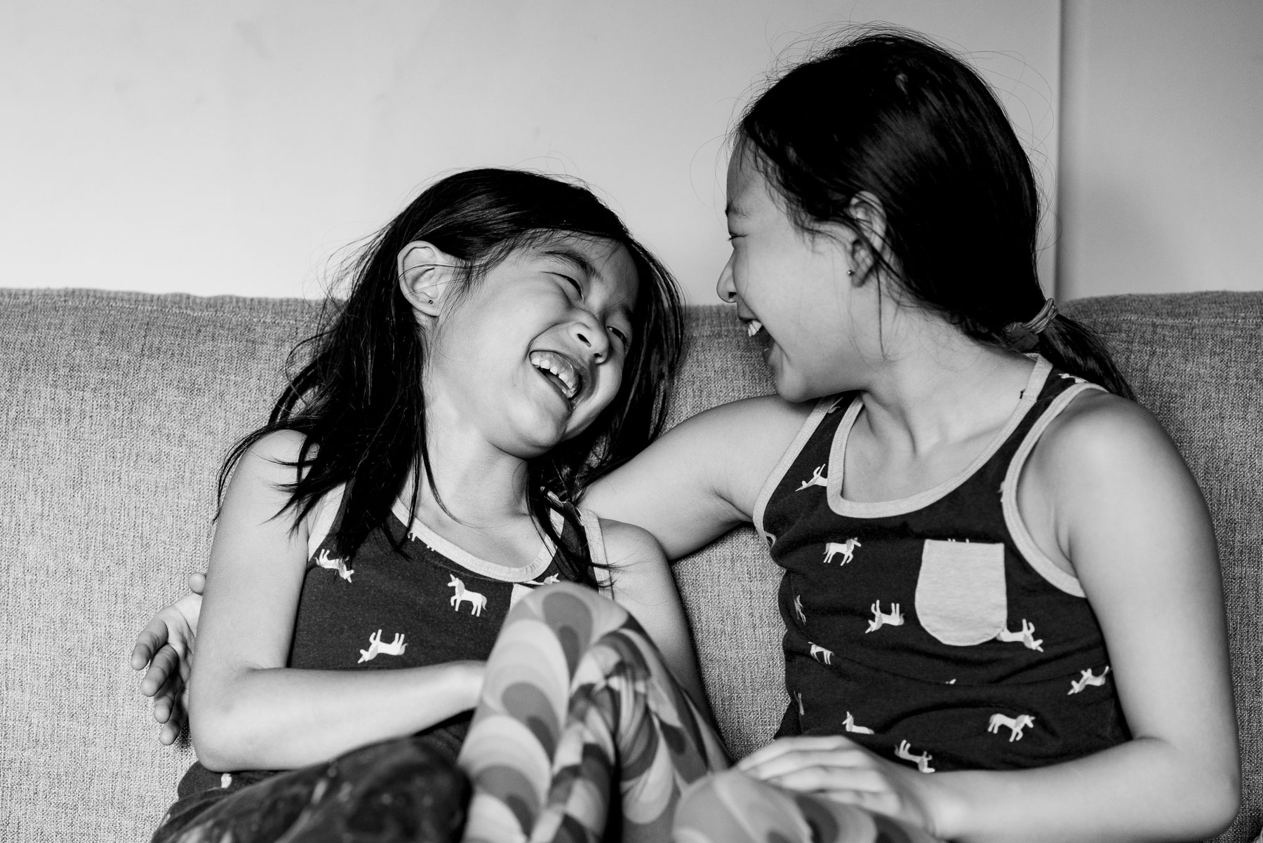 Asian sisters laughing together at home