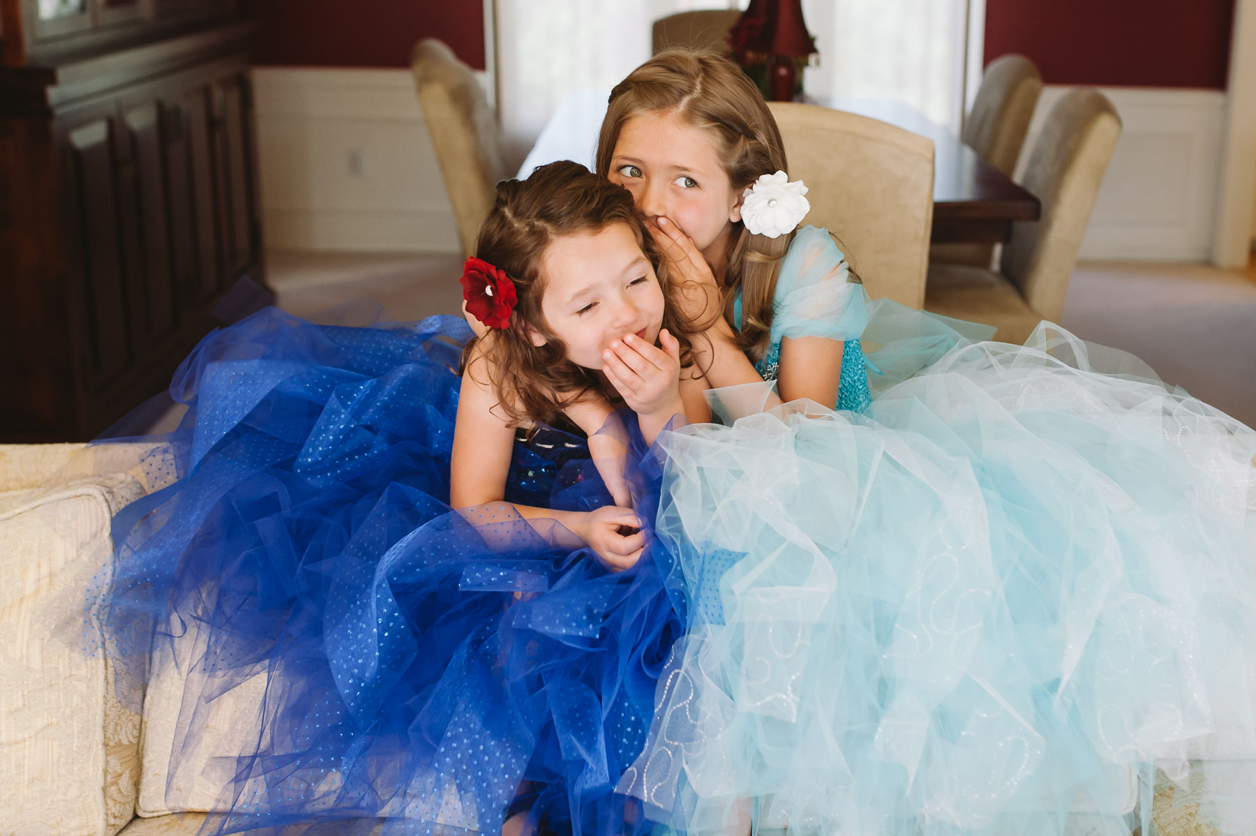 two girls dressed up in Frozen dresses whispering to each other